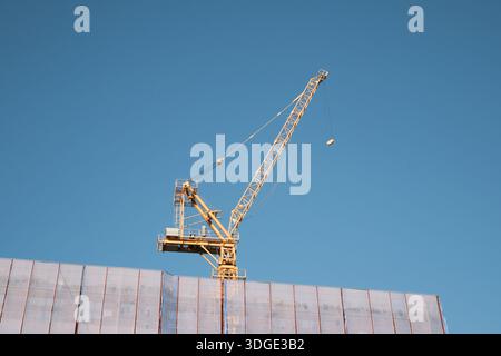 Sokcho, South Korea: Construction crane rising above building site against clear blue summer sky near the East Sea coast Stock Photo