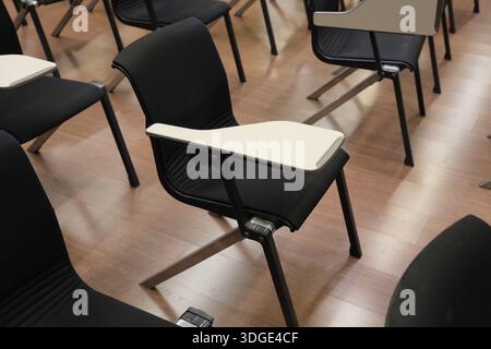 Seoul, South Korea: Empty university lecture hall with rows of modern black chairs and desks prepared for students Stock Photo