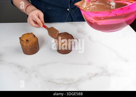 A pastry chef covering small panettone cakes with melted chocolate. Stock Photo