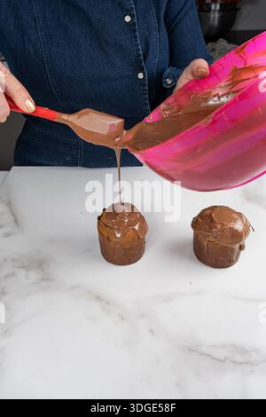 A pastry chef covering small panettone cakes with melted chocolate vertical. Stock Photo