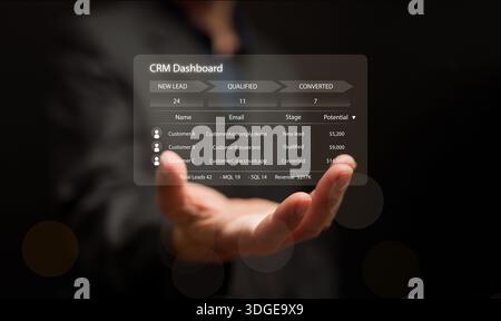 Businessman hand holding CRM dashboard interface with lead management and sales data. Modern customer relationship management concept and software sol Stock Photo