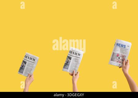 Women with newspapers on yellow background Stock Photo