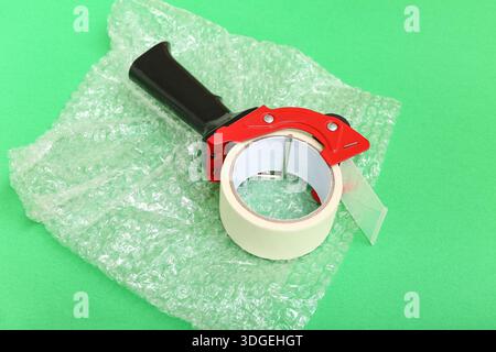 Packing tape dispenser and bubble wrap on green background Stock Photo