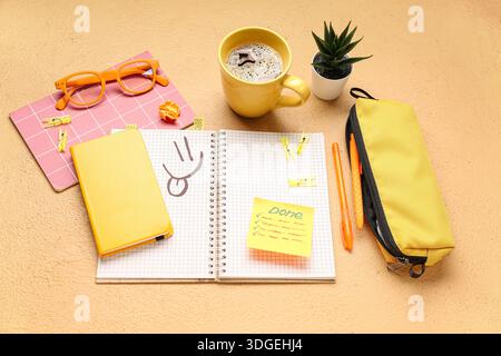 Sticky note with word DONE, stationery, coffee cup and eyeglasses on beige background Stock Photo