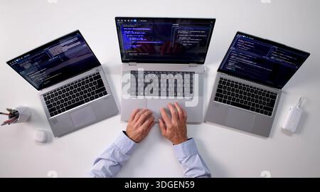 Skilled Programmer Creating Web Software On Multiple Laptops At Office. Stock Photo