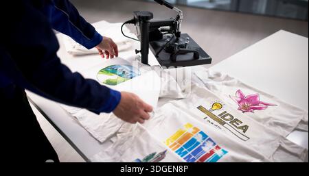 Young Latino Man Begins Custom T-shirt Design Business With Heat Press Machine. Stock Photo
