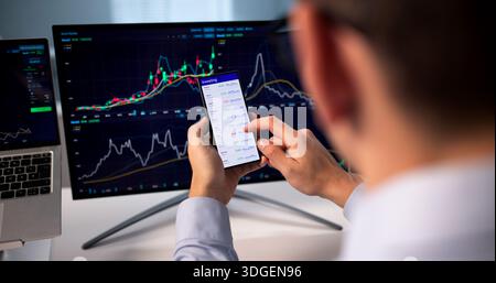 Young Hispanic Businessman Using Mobile App To Trade On Stock Exchange. Stock Photo
