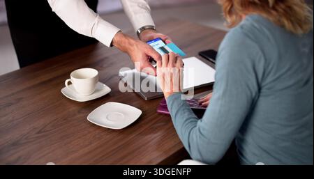 Elderly Woman Using Credit Card To Pay For Coffee Purchase. Stock Photo