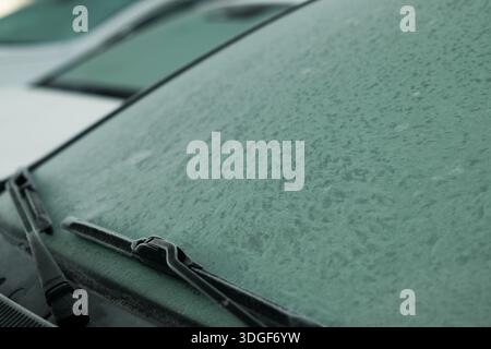 Car windshield covered in thick frost during cold winter morning with wipers Stock Photo