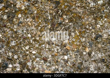 Texture of small brown and grey pebbles embedded in concrete. Rough aggregate stone surface for architectural background or construction design Stock Photo