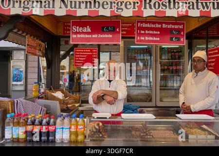 Traditional street food stall selling Original Nürnberger Rostbratwurst and steak in Nuremberg, Germany. Two vendors behind a counter with snacks Stock Photo
