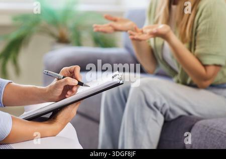 Therapist taking notes while patient gestures during supportive counseling session Stock Photo
