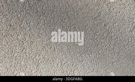 Gray plain monochrome asphalt close-up, with grainy texture and slight shading under bright sunny directional lighting, beautiful textured empty gray Stock Photo
