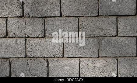 Close-up of concrete block street wall with crack in structure, cracked block masonry, textured background of large foam blocks, brick wall shrinkage Stock Photo