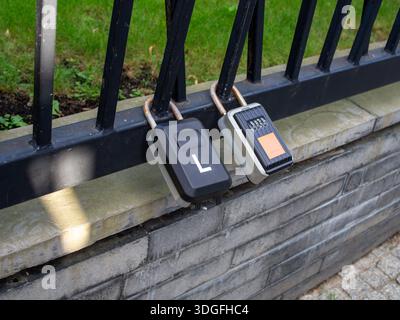 A pair of key lockboxes secured to a fence for holiday rentals or tourist apartments Stock Photo