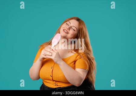 Body Positive Woman Singing, Dancing With Hair Brush Instead Microphone On Blue Stock Photo