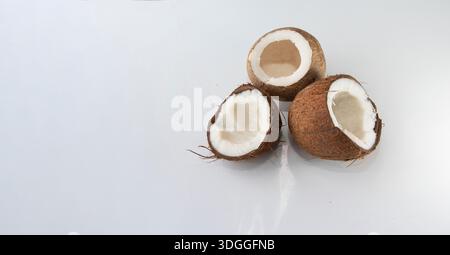 Three halved coconuts with white flesh isolated on clean white background Stock Photo