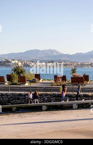Santander, Spain – Nov 19, 2021: People, including children, walk and relax on the sunny waterfront promenade of the Explanada de Gamazo in Santander. Stock Photo