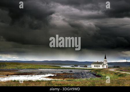 Small church in Nesseby under thick, dramatic clouds in the sky, Nesseby, Finnmark, Norway Stock Photo