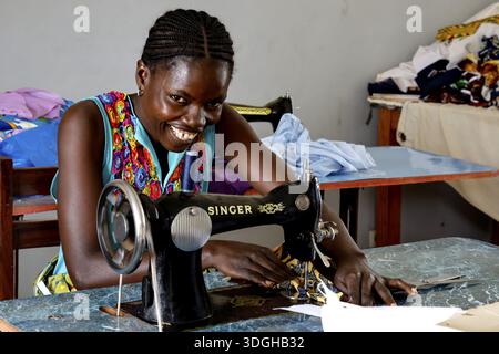 Woman working smiling on a sewing machine in a colorful sewing room, Bouake, null, Cote d'Ivoire Stock Photo