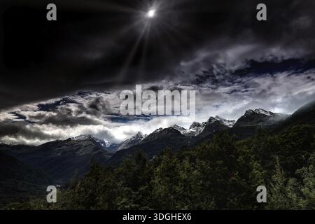 Dramatic snow-covered mountain landscape under a cloudy sky, Milford Road, New Zealand Stock Photo