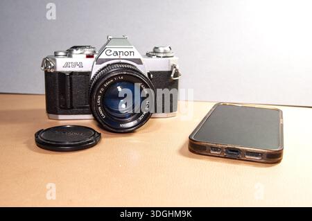 Bristol UK 01-17-2026 A vintage Canon AV-1 camera with a 50mm f/1.4 lens next to a smartphone, representing the evolution of photography technology Stock Photo