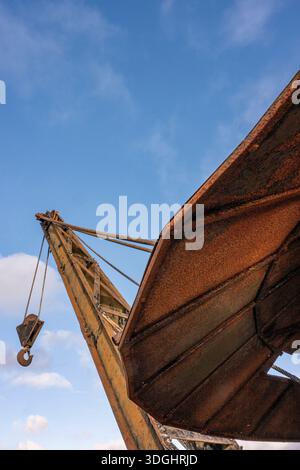 Abstract of rusty and corroded old vintage lifting crane against a blue sky on the dockside in Newport harbour on the isle of wight UK Stock Photo