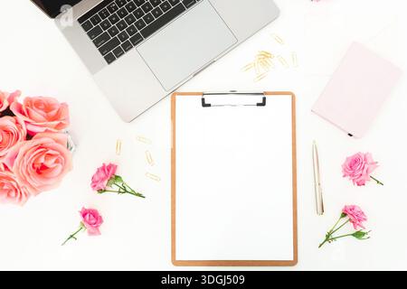 Stylish feminine workspace with laptop, clipboard and roses on white desk, creative home office flat lay Stock Photo