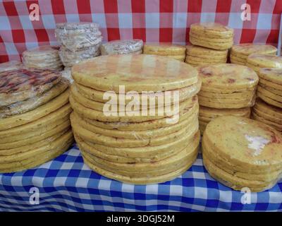 Packs of different sizes arepas for sale on a squared tablecloth, in a stall of the traditional market of the town f Villa de Leyva Stock Photo