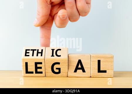Ethic and legal concept. A businessman's hand turning wooden blocks and changing the word ETHIC into  LEGAL.  Business concept. Copy space. Close up Stock Photo