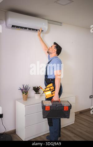 Technician checking air conditioning unit while holding toolbox Stock Photo