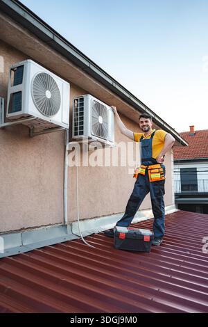 HVAC technician checking air conditioning units on a roof Stock Photo