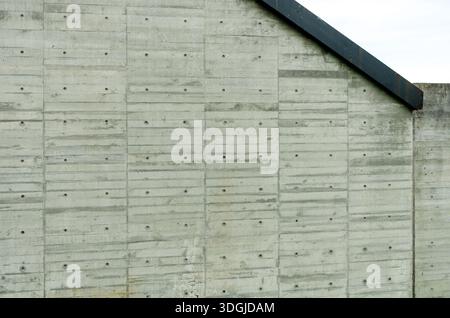 Abstract architectural background showing the texture and pattern of a raw concrete wall with visible formwork lines and tie holes. A minimalist grey Stock Photo