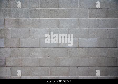 Close-up of a raw, unpainted cinder block wall with large, uniform bricks. Rough texture and neutral tones emphasize an industrial, minimalist style. Stock Photo