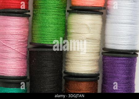 Background of multicolored spools of thread on white background in closeup Stock Photo