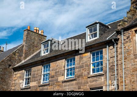 Perspective view of historic stone buildings in St. Andrews with a bright, sunny sky filled with wispy cirrus clouds. Stock Photo