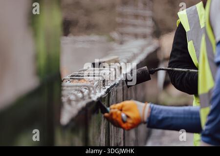 Construction worker welding steel reinforcement bars on concrete structure Stock Photo