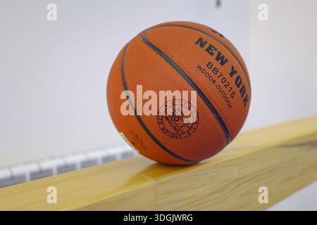 Basketball resting on wooden beam indoors Stock Photo