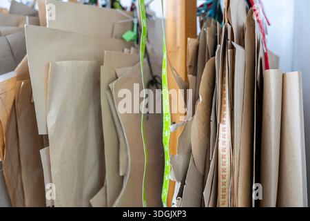 A close-up of a measuring tape hanging with paper sewing patterns in a tailor's workshop. A concept of precision, measurement, and the tools of the fa Stock Photo