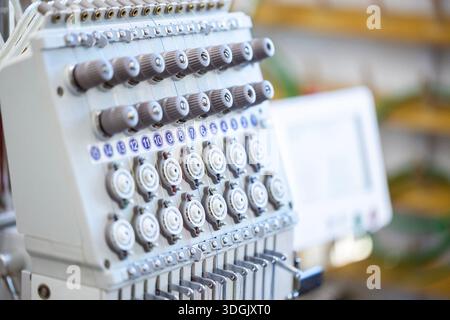 Close-up of the head of a professional multi-needle embroidery machine. Industrial equipment for automated sewing and textile manufacturing in a facto Stock Photo