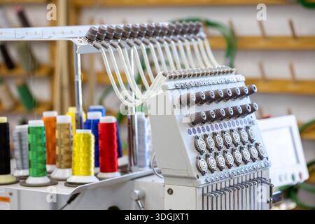 Close-up of the head of a professional multi-needle embroidery machine. Industrial equipment for automated sewing and textile manufacturing in a facto Stock Photo