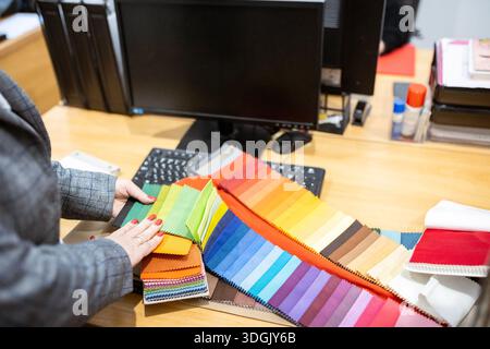 Two designers or a client and a decorator collaborating on a project. They are choosing from a variety of colorful fabric swatches for fashion or inte Stock Photo