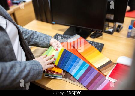 Two designers or a client and a decorator collaborating on a project. They are choosing from a variety of colorful fabric swatches for fashion or inte Stock Photo