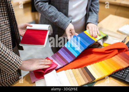Two designers or a client and a decorator collaborating on a project. They are choosing from a variety of colorful fabric swatches for fashion or inte Stock Photo