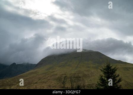 High-angle shot of dramatic low clouds and mist clinging to the green slopes of the Black Cuillin mountains in Scotland. Stock Photo