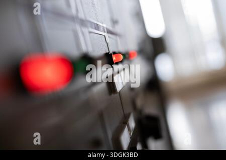 A close-up, selective focus view of a glowing red indicator light on an old industrial control panel. This light signals the status of machinery, powe Stock Photo