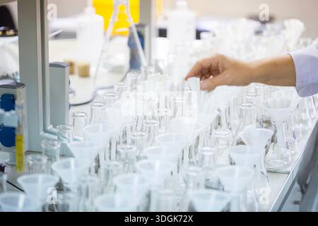 Laboratory worker hand arranges white paper filters in glass flasks with funnels on the table preparing for chemical liquid filtration process in the Stock Photo