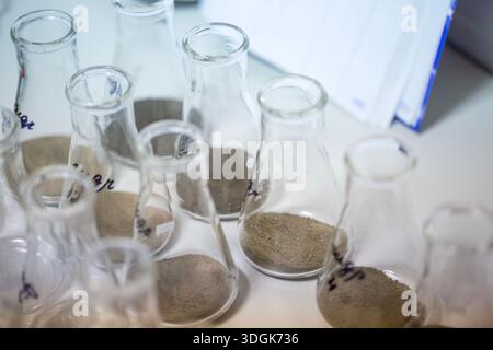 Close up high angle view of glass Erlenmeyer flasks with dry soil samples inside standing on the white table ready for chemical analysis in the agricu Stock Photo
