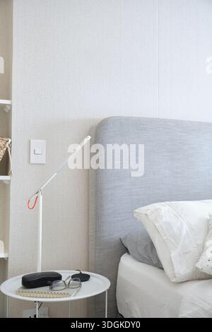 Bedroom interior showcasing minimal design with a functional light source and reading accessories Stock Photo