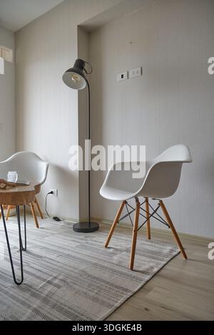 Minimalist living room interior featuring modern eames style chairs and floor lamp Stock Photo